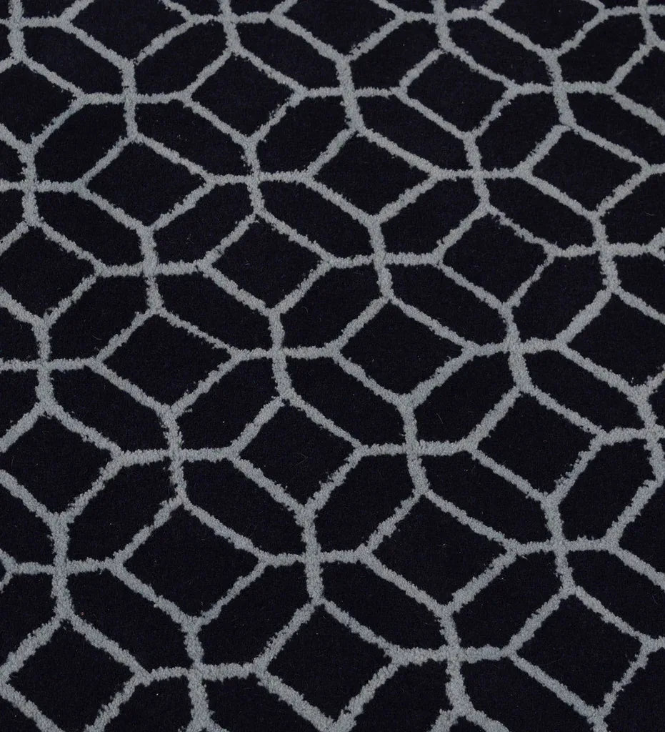 A close-up of a textured fabric or carpet featuring a repeating geometric pattern of dark navy blue hexagons outlined in light gray.