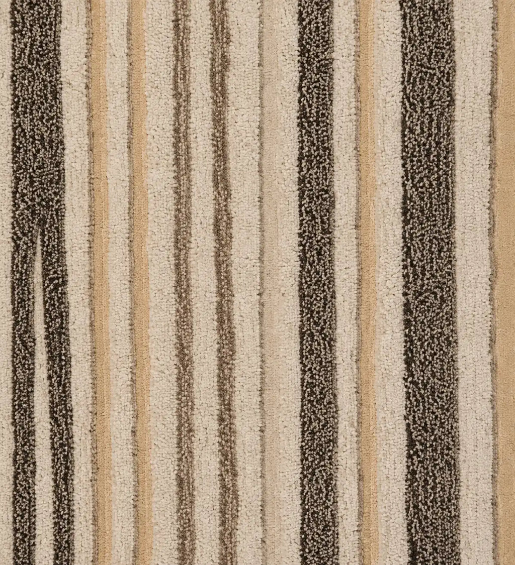A close-up of a textured rug or fabric with vertical stripes in beige, tan, brown, and dark charcoal gray.