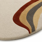 Close-up of a textured rug with wavy pattern in brown, beige, and gray on a neutral background.