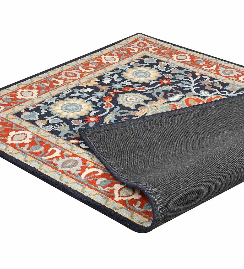 Orange and blue traditional hand-tufted rug with floral patterns and dark border, corner folded