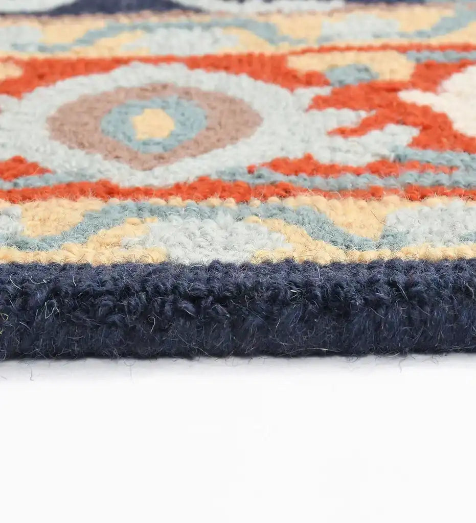 Close-up of orange and blue hand-tufted traditional rug with geometric pattern and thick navy border