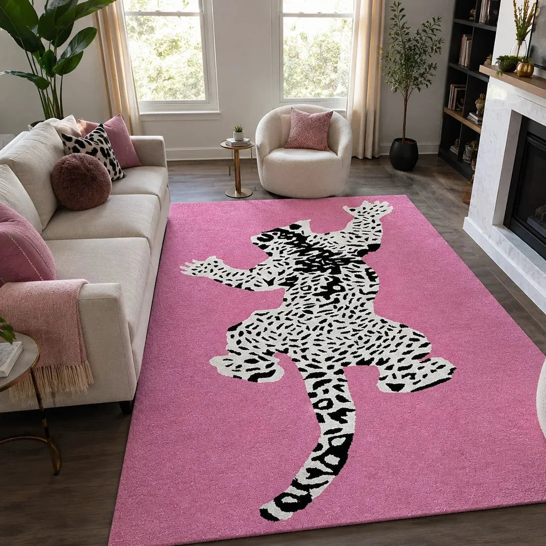 A pink area rug with a large black-and-white spotted animal silhouette design, shown in a styled living room with a sofa, chairs, windows, and fireplace.